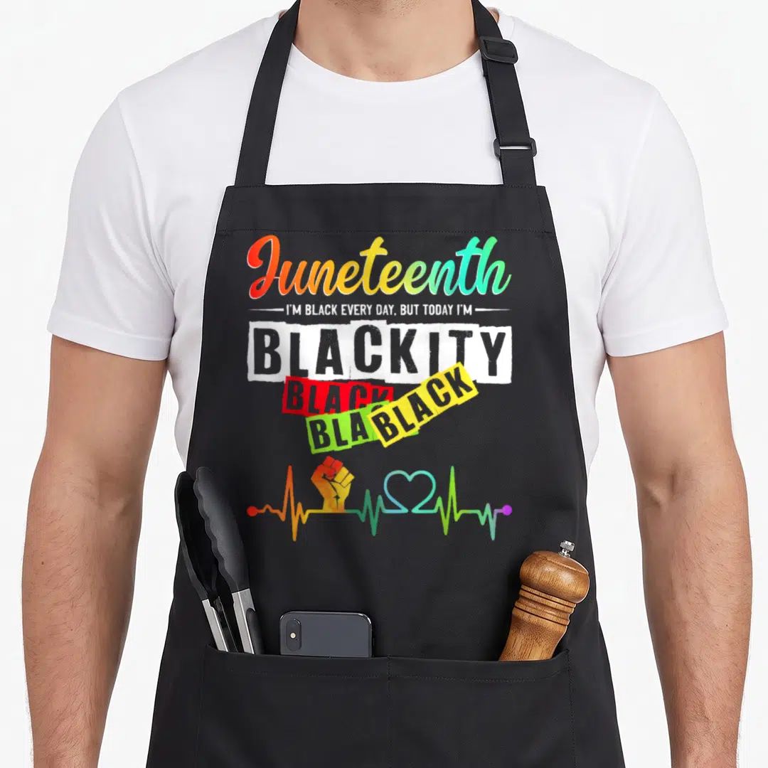 Blackity african american aprons - Juneteenth stacked text with rainbow fist and heartbeat line on black bib — shown on a black cotton canvas apron against a white background