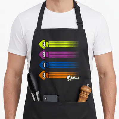 Streak squid apron - Four cartoon squid arrows in lime, purple, blue, and orange with trailing ink lines — shown on a black cotton canvas apron against a white background