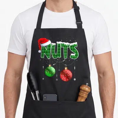 Chest nut couples christmas aprons - NUTS in green plaid with Santa hat, two hanging ornaments, and snowflakes — shown on a black cotton canvas apron against a white background