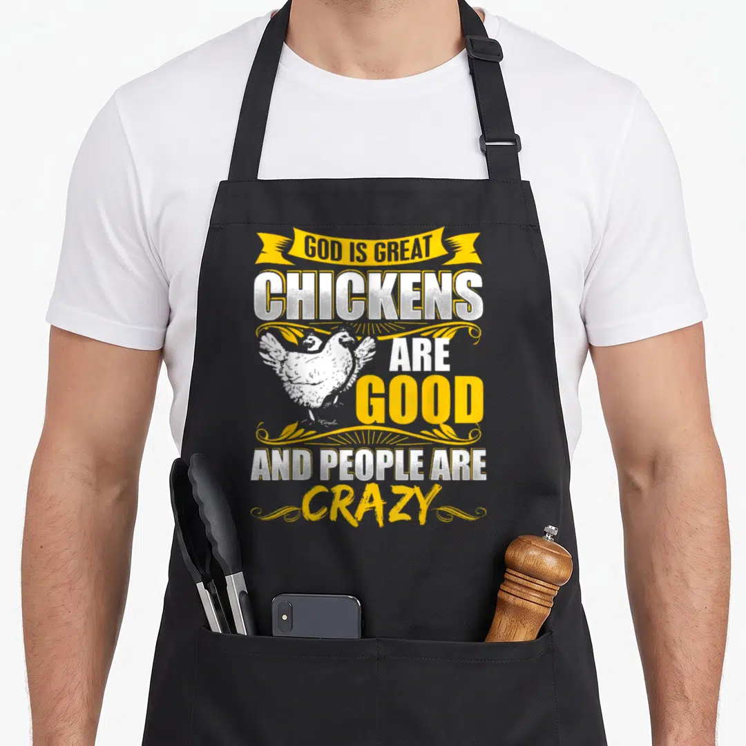 Funny god chicken apron - Stacked yellow and white text with two white chickens and decorative swirls — shown on a black cotton canvas apron against a white background