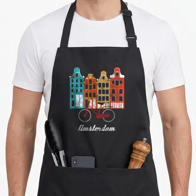 Europische bicycle apron - Four colorful buildings, red bicycle, white Amsterdam text, retro style — shown on a black cotton canvas apron against a white background