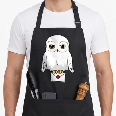 Portrait cartoon apron - White cartoon owl with yellow eyes standing on envelope with red seal — shown on a black cotton canvas apron against a white background