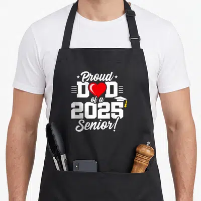 Class senior graduation year apron - White text Proud Dad of a 2025 Senior with red heart and cap on black apron — shown on a black cotton canvas apron against a white background
