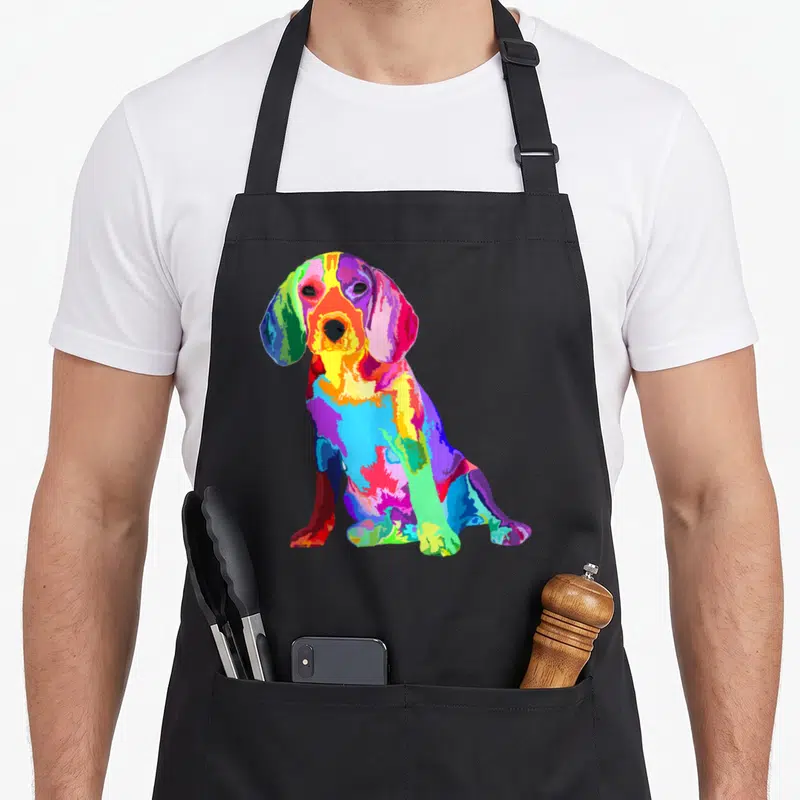 Colorful beagle apron - Multicolored pop-art beagle sitting in blue red yellow green and purple — shown on a black cotton canvas apron against a white background
