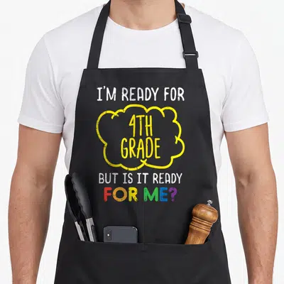 Ready grade fourth apron - Text reading I'm Ready for 4th Grade But Is It Ready For Me in white yellow and rainbow — shown on a black cotton canvas apron against a white background