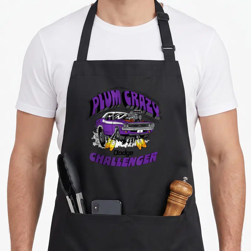 Challenger dodge apron - Purple cartoon Dodge Challenger with exposed engine, yellow flames, and arched PLUM CRAZY text — shown on a black cotton canvas apron against a white background