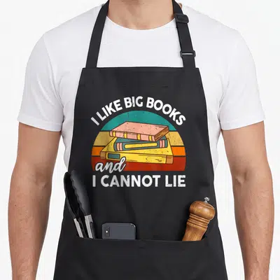 Cannot teacher apron - Retro stack of three books with I Like Big Books and I Cannot Lie text arching over a colorful — shown on a black cotton canvas apron against a white background