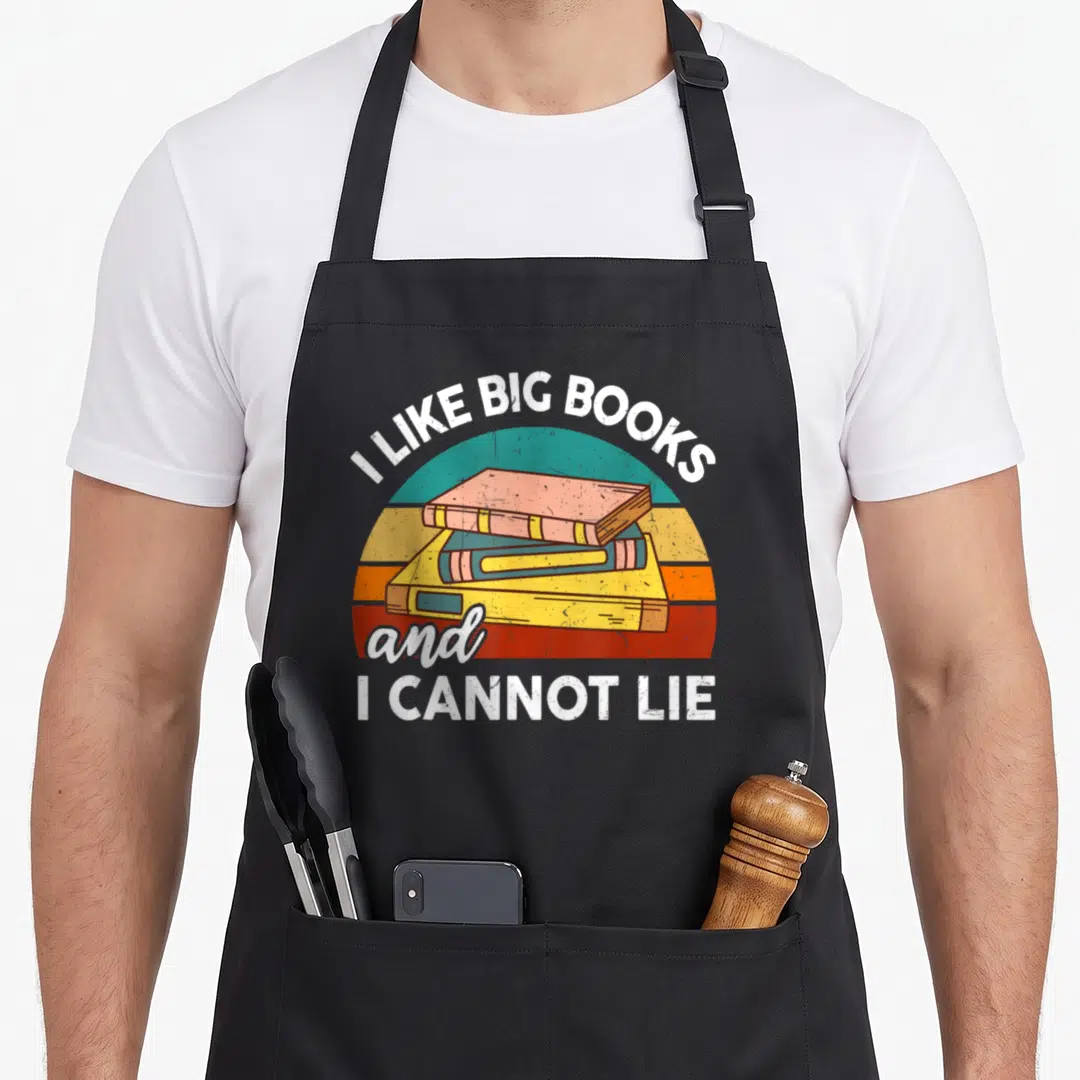 Cannot teacher apron - Retro stack of three books with I Like Big Books and I Cannot Lie text arching over a colorful — shown on a black cotton canvas apron against a white background