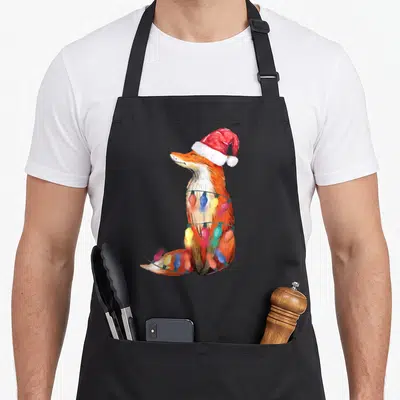 Fox christmas lights apron - Watercolor fox in red santa hat wrapped in blue yellow and red christmas lights — shown on a black cotton canvas apron against a white background