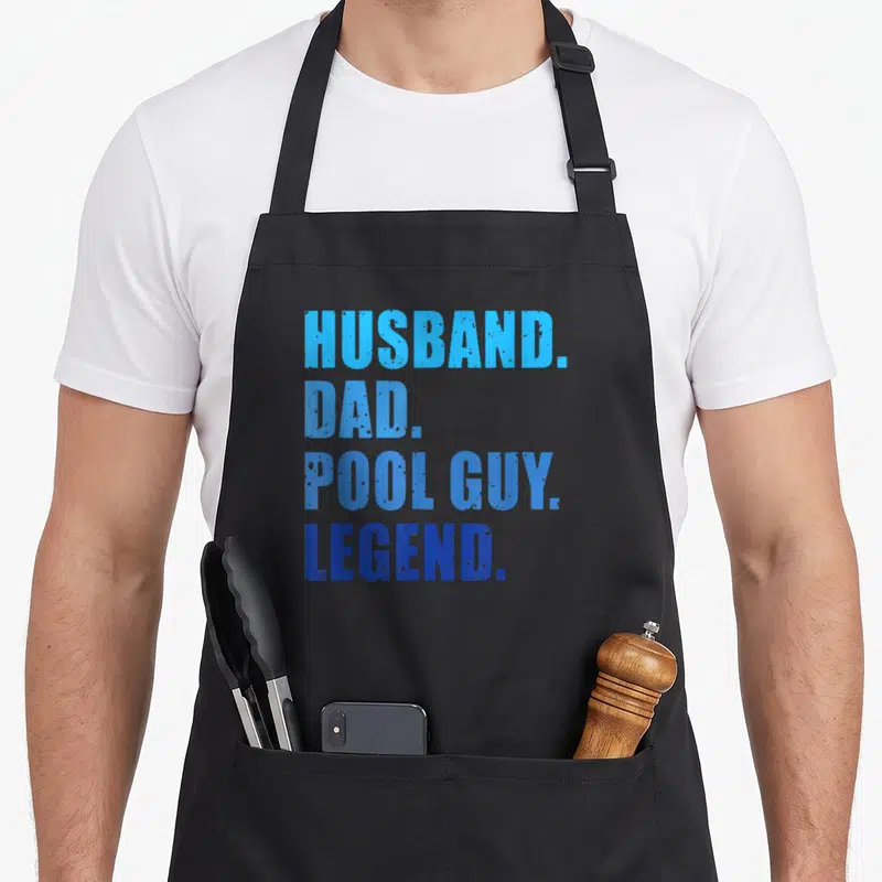 Pool legend husband apron - Stacked blue text reading HUSBAND. DAD. POOL GUY. LEGEND. on grey background — shown on a black cotton canvas apron against a white background