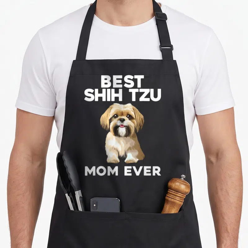 Cute shih dog apron - Cartoon Shih Tzu dog with Best Shih Tzu Mom Ever text in white tan black — shown on a black cotton canvas apron against a white background