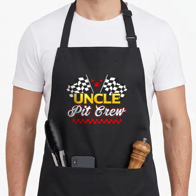 Family uncle car apron - UNCLE Pit Crew text with checkered flags and three red stars in cartoon style — shown on a black cotton canvas apron against a white background