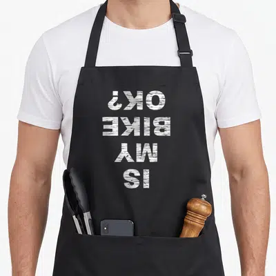 Bike cycling apron - White stacked text reading Is My Bike OK printed upside down — shown on a black cotton canvas apron against a white background