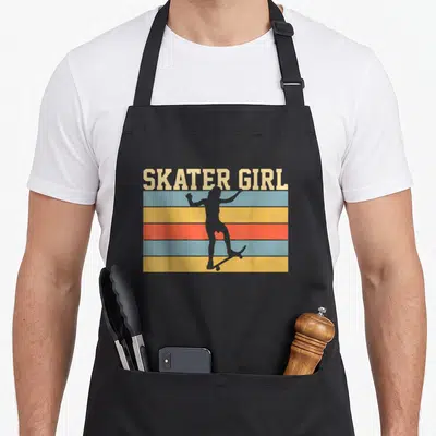 Funny skateboard skateboarding lover apron - SKATER GIRL text over colored stripes with a grey girl silhouette — shown on a black cotton canvas apron against a white background