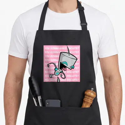Invader crackers apron - Grey robot with teal eyes on pink background with repeated white text — shown on a black cotton canvas apron against a white background