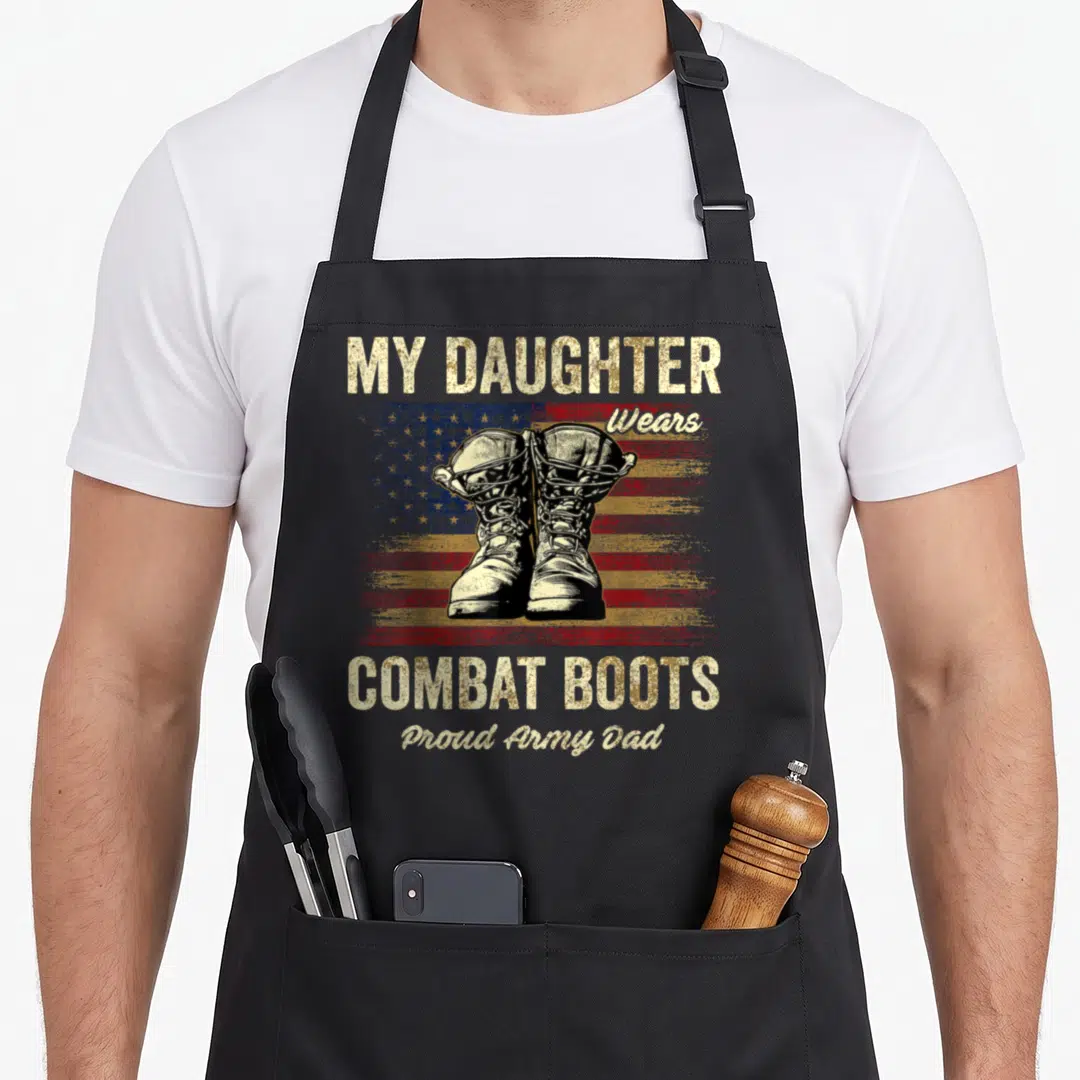 Combat dad and daughter aprons - Distressed US flag behind combat boots with My Daughter Wears Combat Boots Proud Army — shown on a black cotton canvas apron against a white background