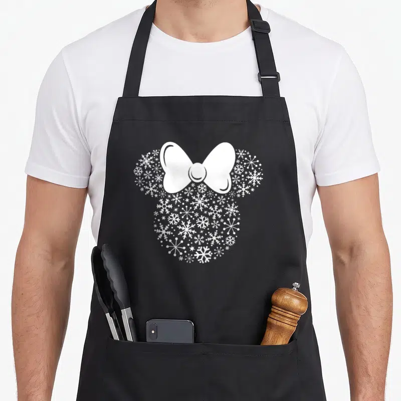 Icon winter apron - White bow and snowflake mouse head silhouette on black fabric — shown on a black cotton canvas apron against a white background