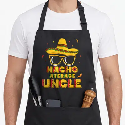 Nacho mayo apron - Sombrero, glasses, NACHO AVERAGE UNCLE text, chili peppers, confetti in yellow red green — shown on a black cotton canvas apron against a white background