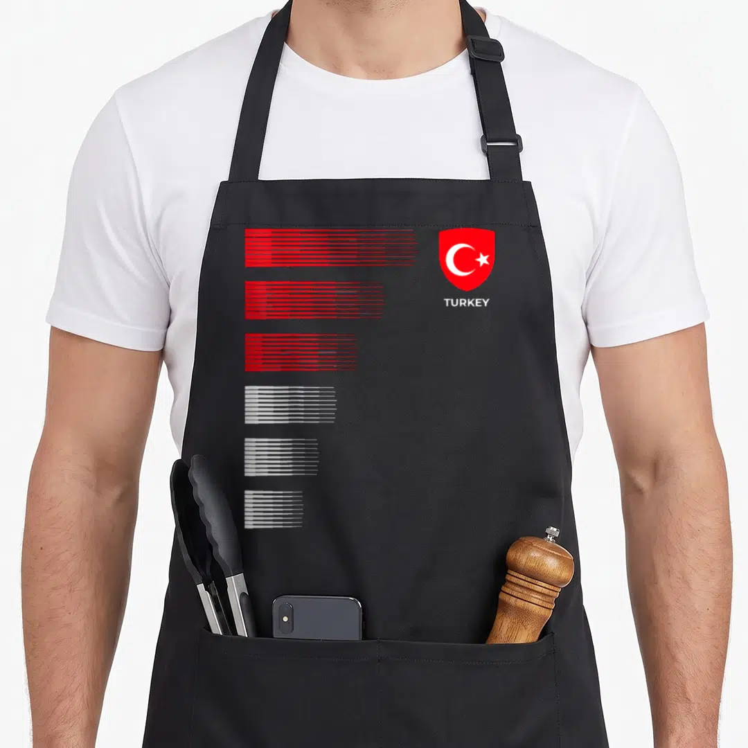 Emblem turkey apron - Red shield with white crescent star and TURKEY text beside six groups of red and white horizontal — shown on a black cotton canvas apron against a white background