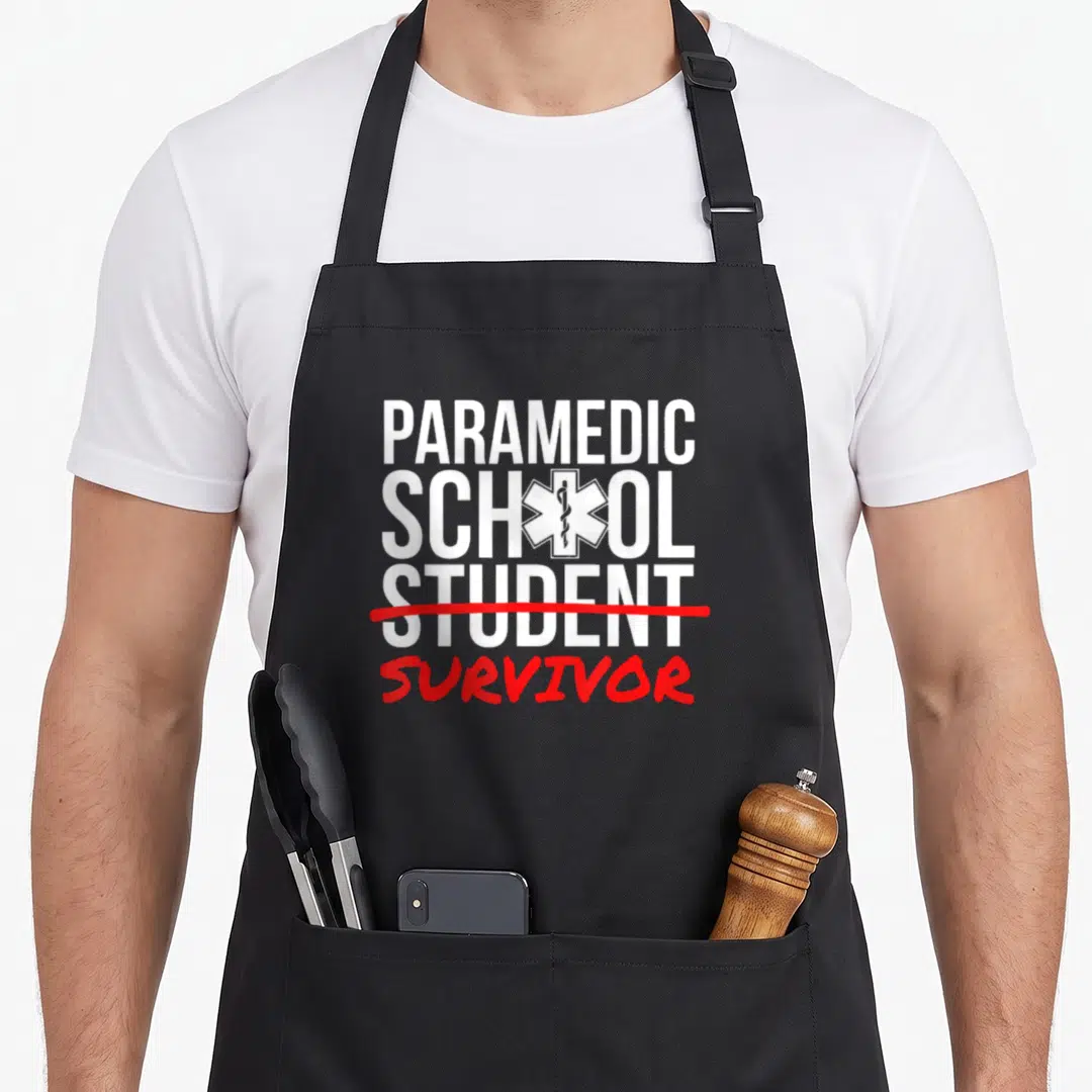 Paramedic student aprons - Text reading Paramedic School Student Survived with Star of Life symbol — shown on a black cotton canvas apron against a white background