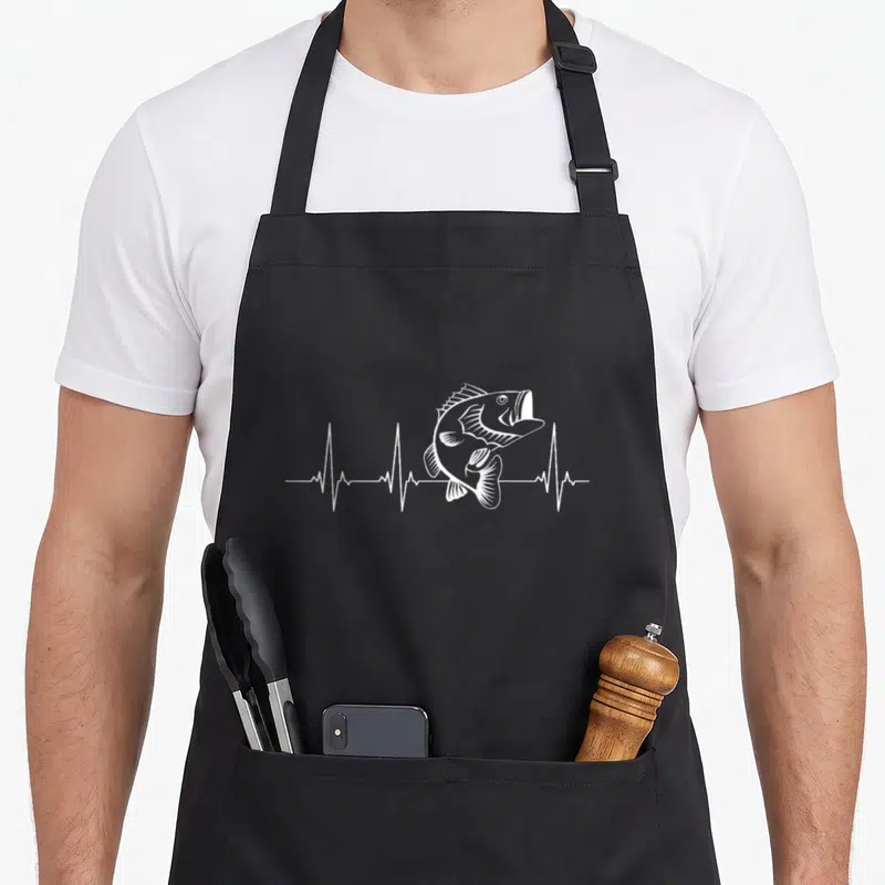 Heartbeat fishing aprons - White line-art bass jumping from a heartbeat EKG pulse line — shown on a black cotton canvas apron against a white background