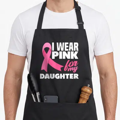 Vintage daughter breast cancer awareness aprons - Pink ribbon graphic next to white I WEAR PINK for my DAUGHTER — shown on a black cotton canvas apron against a white background