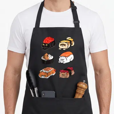 Sushi cat apron - Six cartoon Persian cats styled as sushi in orange, white, black, and red — shown on a black cotton canvas apron against a white background