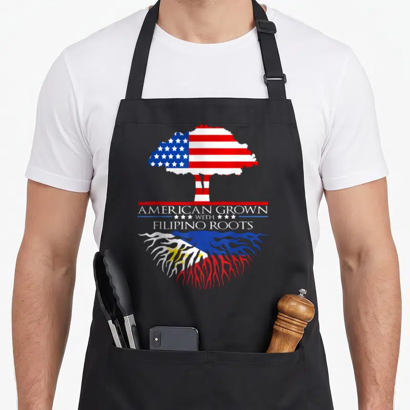 Tree philippine american flag apron - Tree with US flag canopy and Philippine flag roots above AMERICAN GROWN — shown on a black cotton canvas apron against a white background