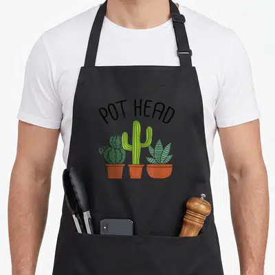 Potted gardener apron - POT HEAD text over three green cacti in terracotta pots — shown on a black cotton canvas apron against a white background