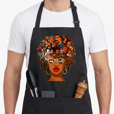 Root pride apron - Portrait with curly hair and sunglasses reading my roots — shown on a black cotton canvas apron against a white background