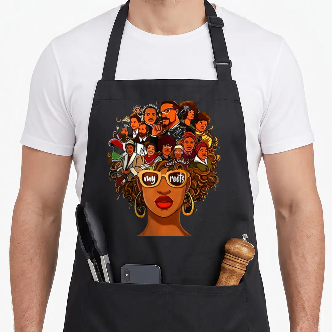 Root pride apron - Portrait with curly hair and sunglasses reading my roots — shown on a black cotton canvas apron against a white background