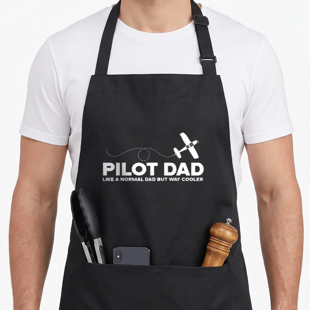 Normal airplane apron - White airplane with dotted loop trail above bold Pilot Dad text — shown on a black cotton canvas apron against a white background
