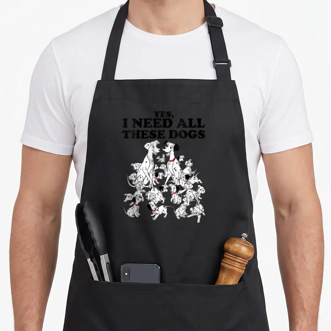 Dalmatian these dog apron - Yes I Need All These Dogs text above cartoon Dalmatian puppies with red collars — shown on a black cotton canvas apron against a white background