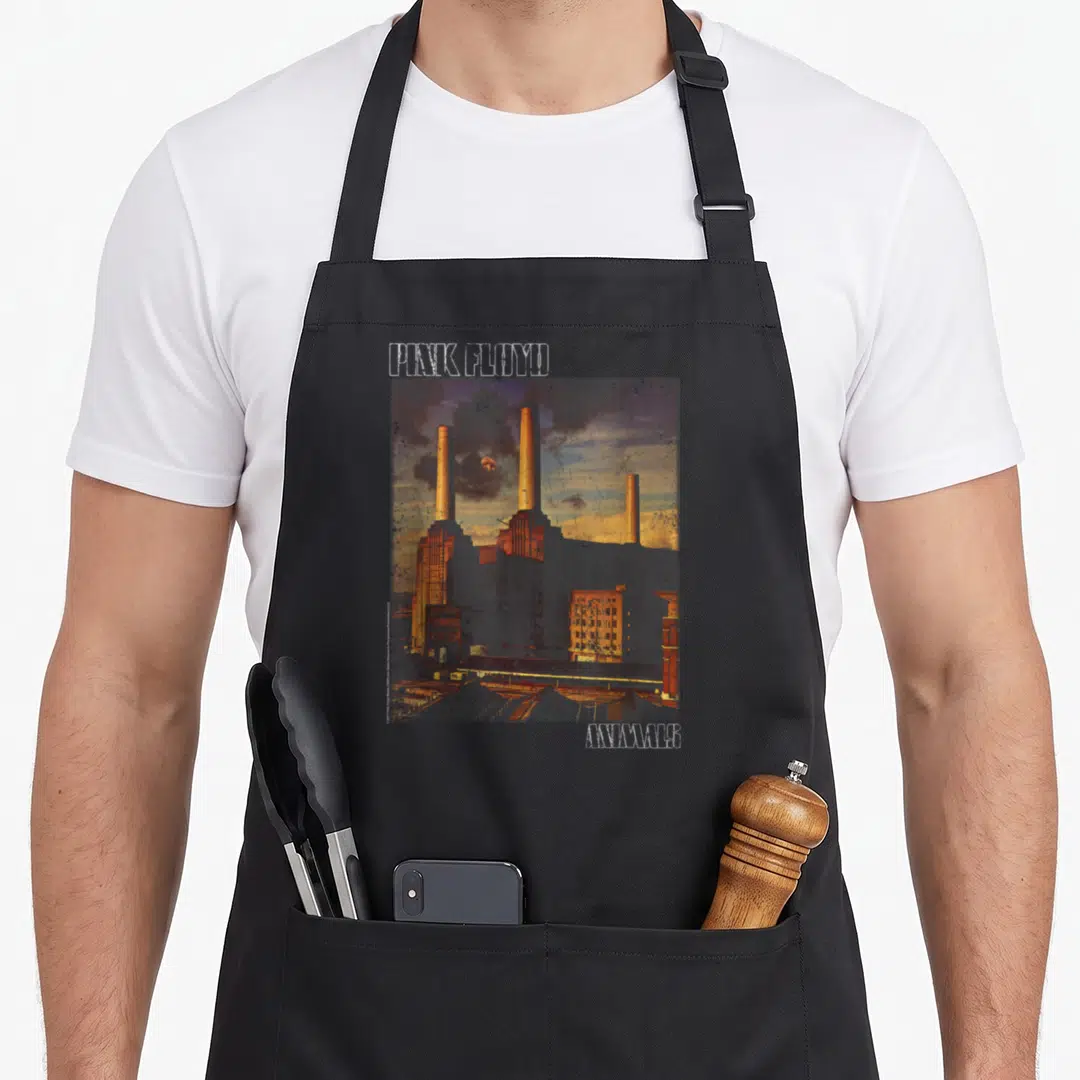 Floyd animal apron - Pink Floyd Animals power station photo print with white outline lettering above and below — shown on a black cotton canvas apron against a white background