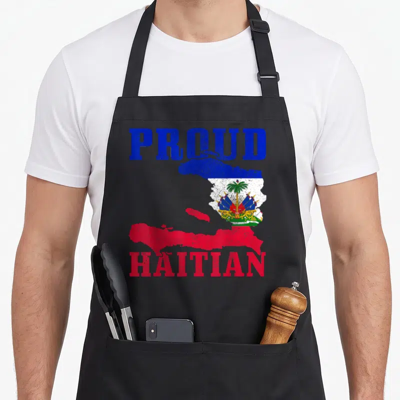 Haiti proud pride apron - Distressed PROUD HAITIAN text framing a map of Haiti filled with the flag's blue red white — shown on a black cotton canvas apron against a white background