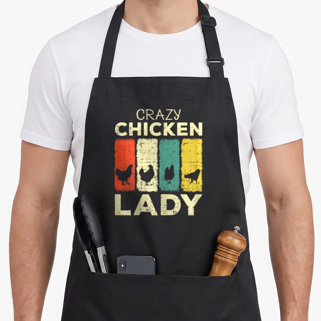 Wildlife chicken apron - CRAZY CHICKEN LADY text with four colored distressed stripes containing chicken silhouettes — shown on a black cotton canvas apron against a white background