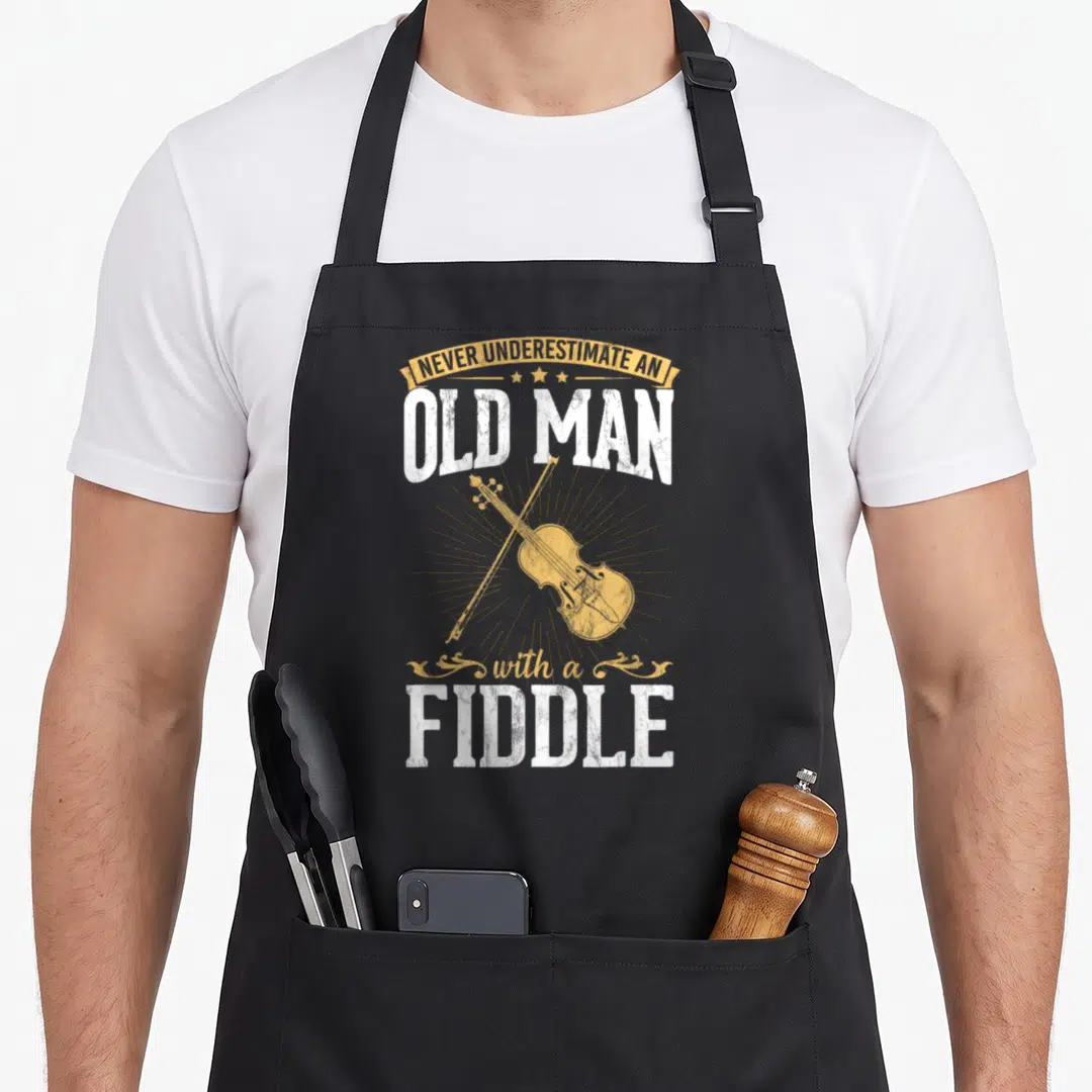 Underestimate musical apron - Yellow sunburst with fiddle and bow surrounded by distressed white text reading NEVER — shown on a black cotton canvas apron against a white background