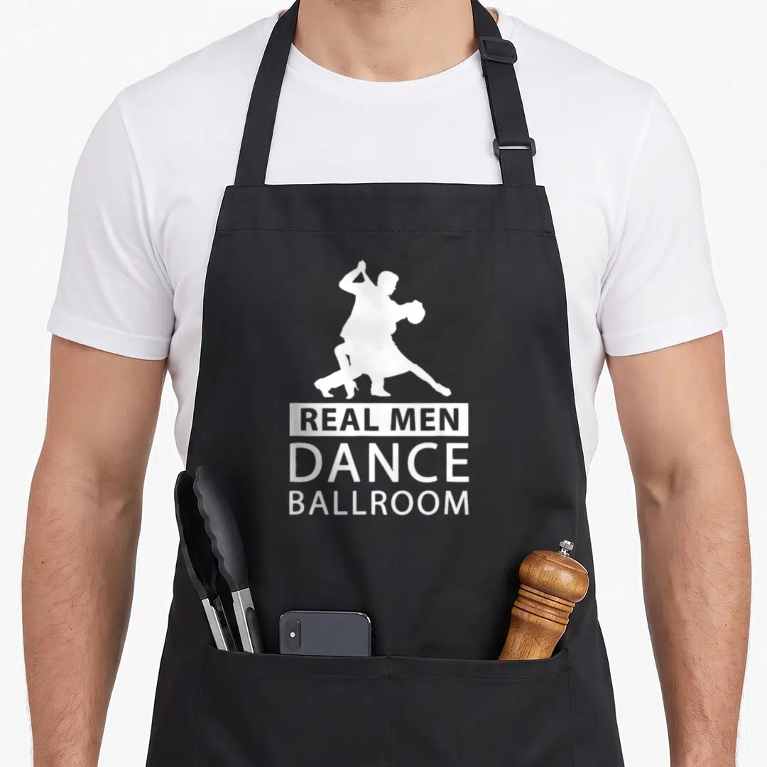 Dance ballroom addict apron - White silhouette of dancing couple above stacked text reading Real Men Dance Ballroom — shown on a black cotton canvas apron against a white background