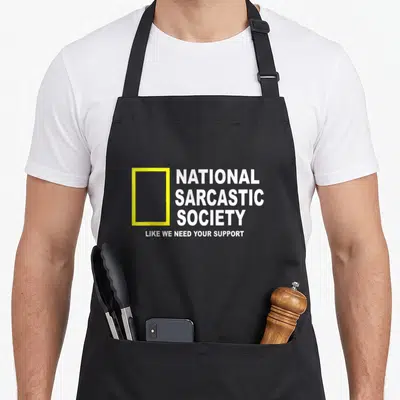 National sarcastic apron - Yellow rectangle next to stacked white text National Sarcastic Society Like We Need Your — shown on a black cotton canvas apron against a white background