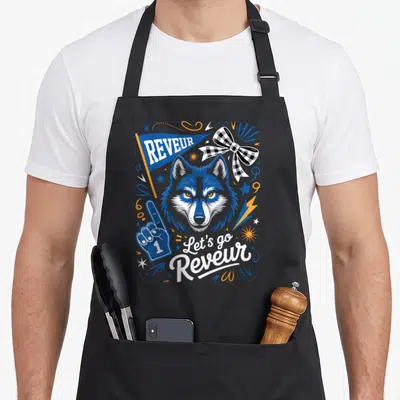 Blue dreamer apron - Cartoon wolf head with pennant, foam finger, and text in blue and orange — shown on a black cotton canvas apron against a white background