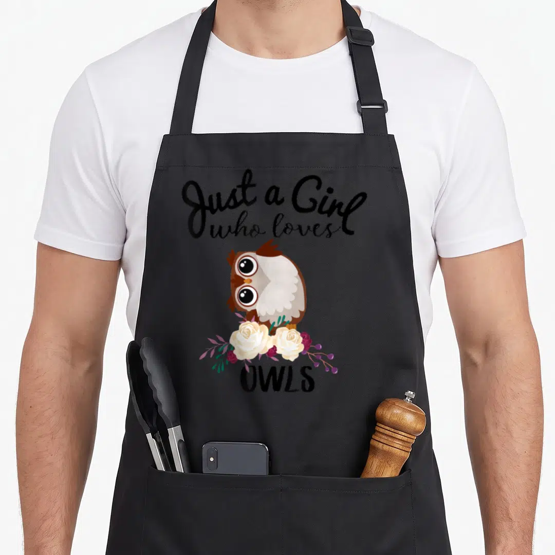 Owl bird apron - Cartoon owl on roses with Just a Girl who loves OWLS text — shown on a black cotton canvas apron against a white background