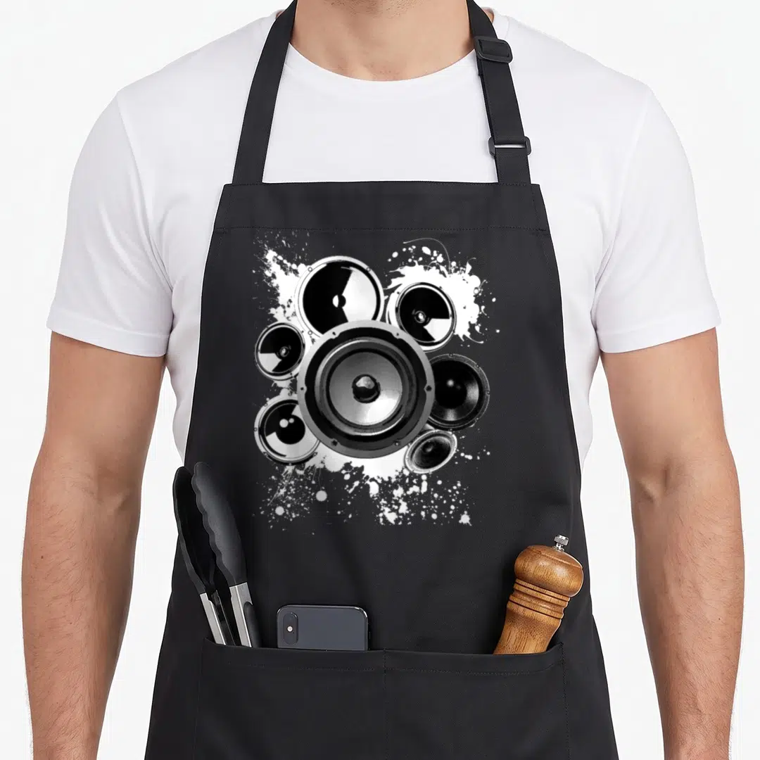 Speaker crew apron - Six realistic speakers and white paint splatters on black fabric — shown on a black cotton canvas apron against a white background