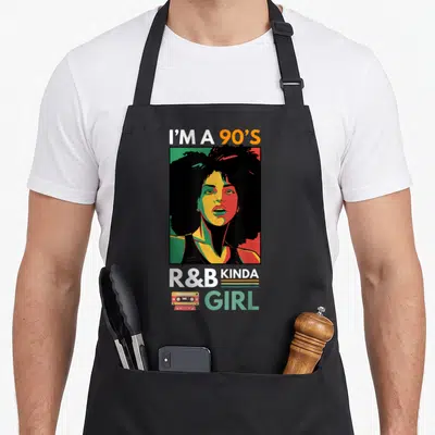 Kinda r aprons - Stylized portrait of a woman with cassette tape and I'M A 90'S R&B KINDA GIRL text — shown on a black cotton canvas apron against a white background