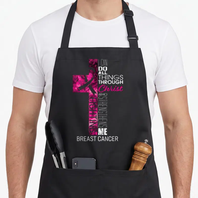 Cross breast cancer awareness aprons - Pink mottled cross with awareness ribbon and stacked white and purple typography — shown on a black cotton canvas apron against a white background