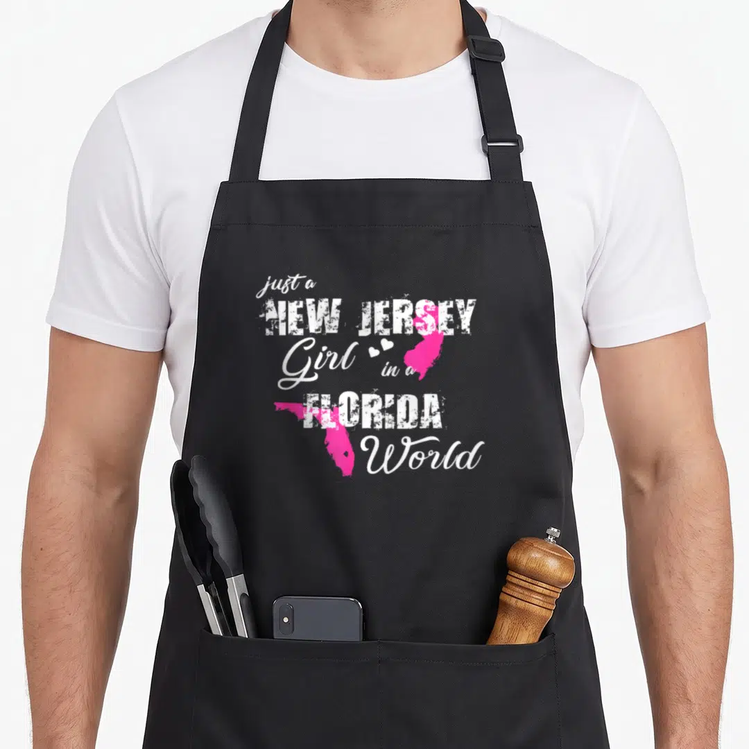 Jersey florida pride apron - White text just a NEW JERSEY Girl in a FLORIDA World with pink state maps and two white — shown on a black cotton canvas apron against a white background