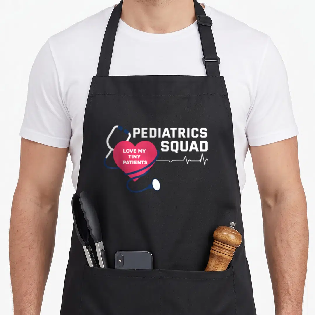 Pediatric care nurse apron - Navy blue stethoscope wraps pink heart containing LOVE MY TINY PATIENTS text next — shown on a black cotton canvas apron against a white background