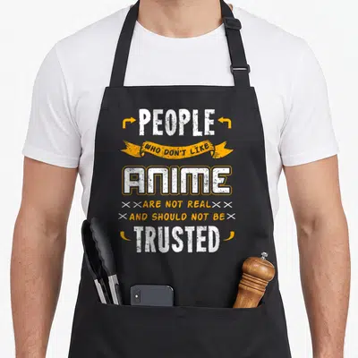 Retro japanese anime apron - Stacked white and orange text reading People Who Don't Like Anime Are Not Real And Should — shown on a black cotton canvas apron against a white background