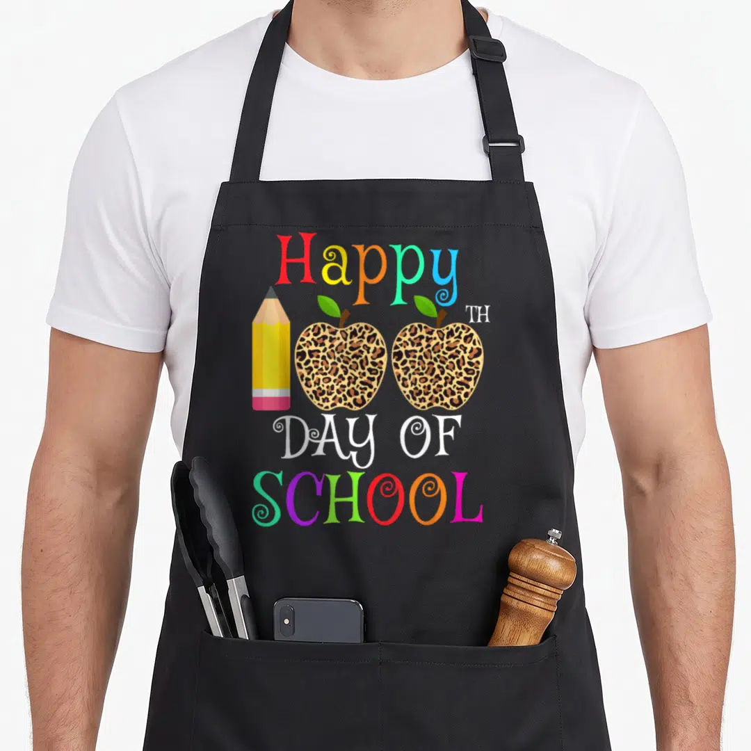 Leopard teacher apron - Two leopard print apples and pencil with Happy 100th Day of School text — shown on a black cotton canvas apron against a white background