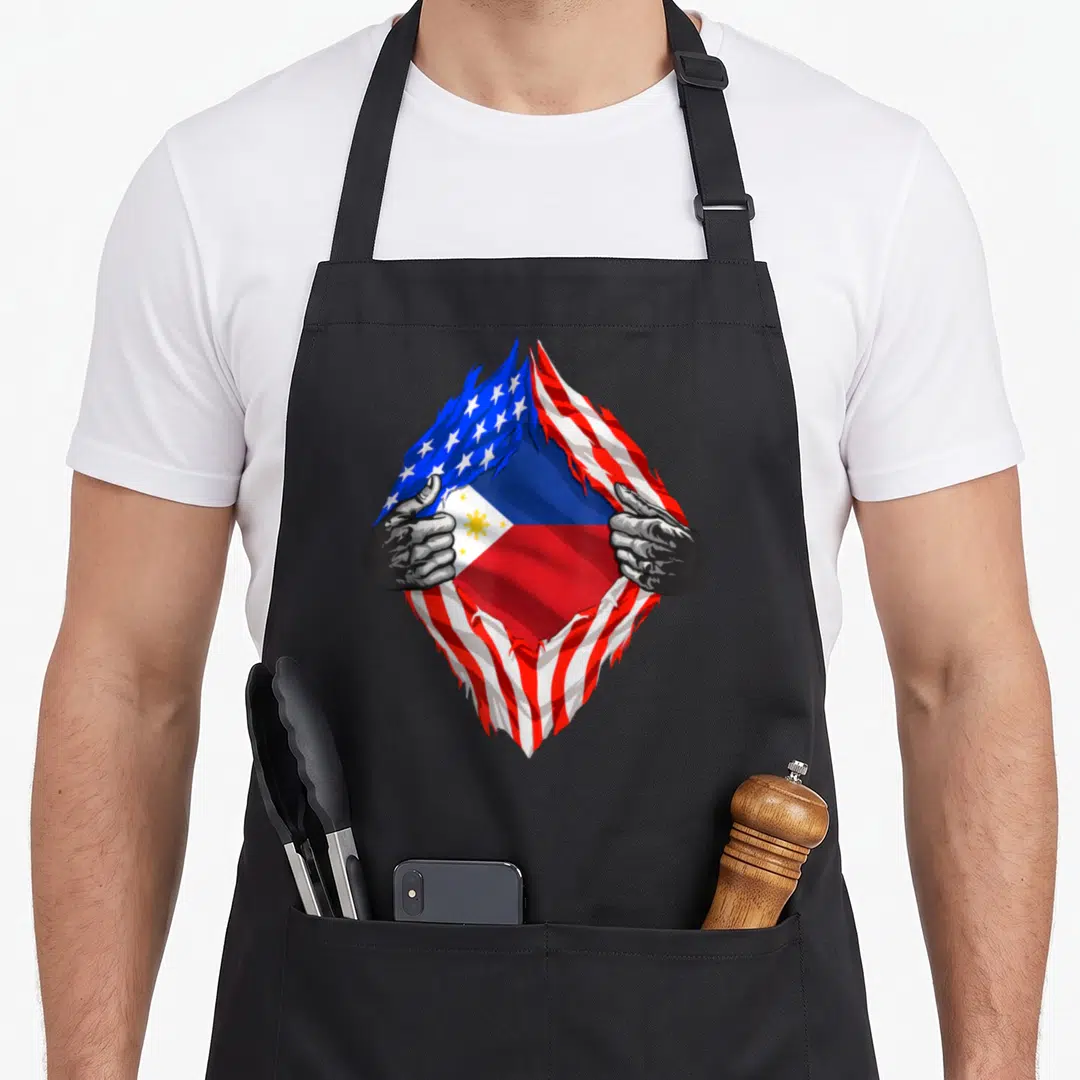 Philippine pinoy american flag apron - Hands tearing US flag to reveal Philippines flag with blue red white yellow sun — shown on a black cotton canvas apron against a white background
