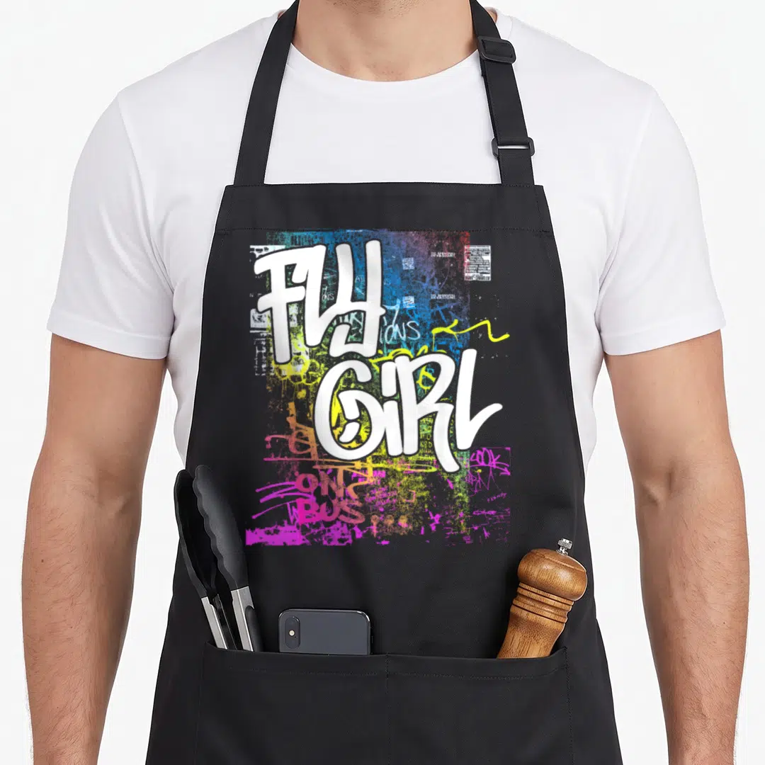 Graffiti hip apron - FLY GIRL white graffiti text over blue yellow pink green paint splatters — shown on a black cotton canvas apron against a white background